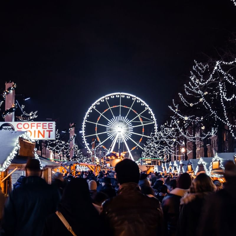 Christmas Market in Brussels with Ferris wheel and decorations at night near Warwick Brussels