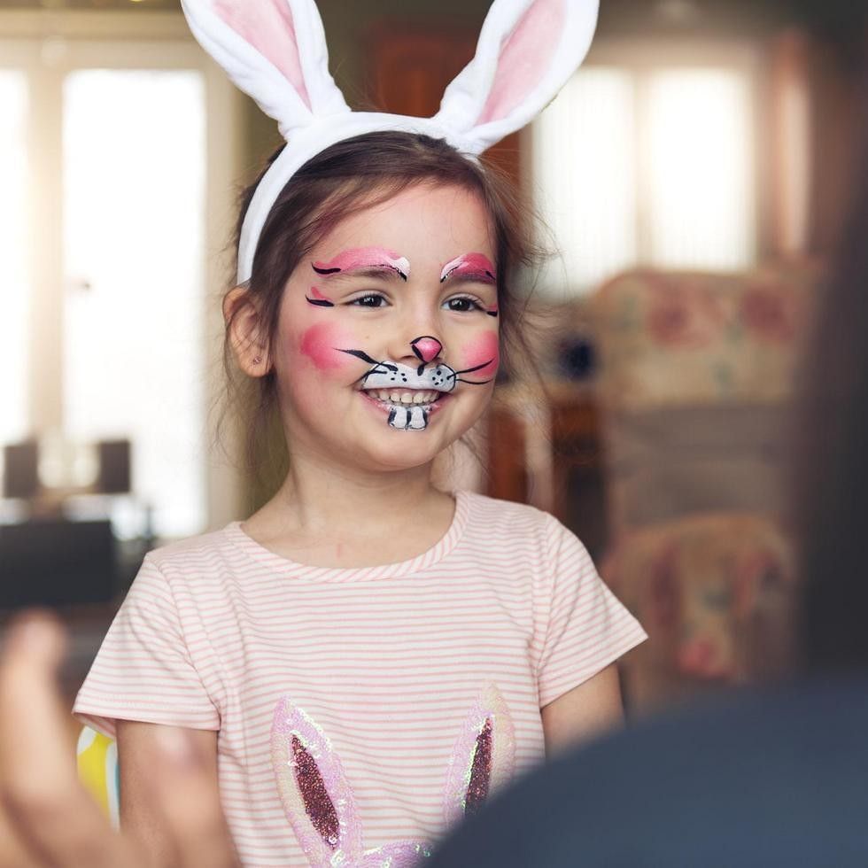 Bambina con viso dipinto da coniglio e orecchie per Carnevale