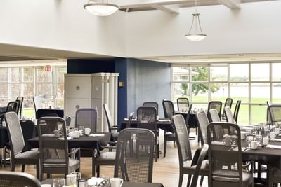 Gordan Room with black tables and mesh chairs near large windows at Rodd Brudenell River Resort