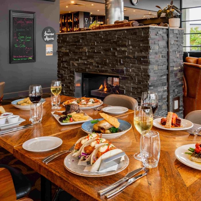 Karinyas Restaurant interior with an array of dishes on a table, fireplace in the background at Mercure Kooindah Waters