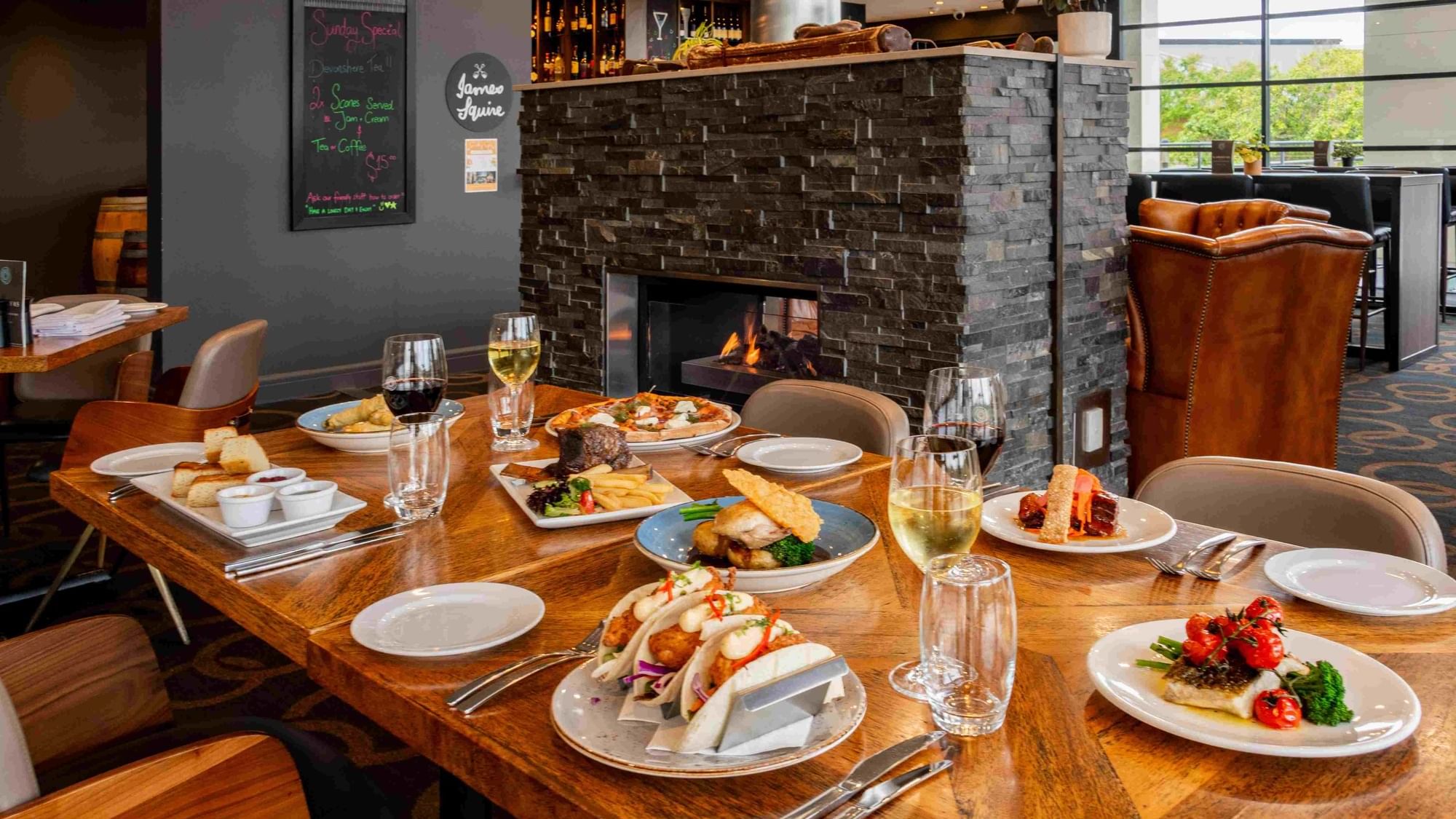 Karinyas Restaurant interior with an array of dishes on a table, fireplace in the background at Mercure Kooindah Waters