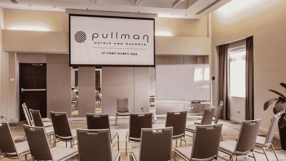 Chairs arranged in Nexus 1 & 2 Room with a wide screen at Sydney Olympic Park