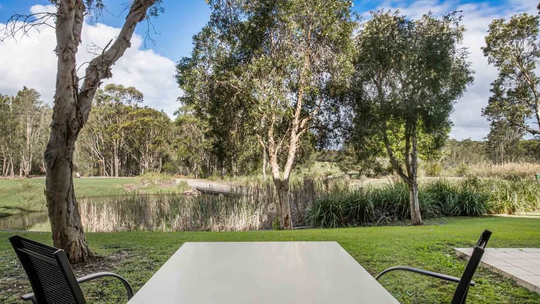 One Bedroom Apartment View of a serene park from behind a table with two chairs at Mercure Kooindah Waters