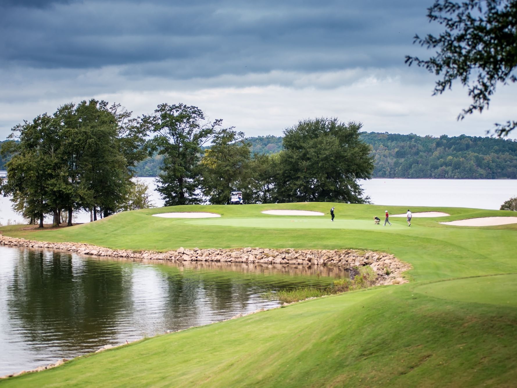 people playing on golf course hole with view of lake