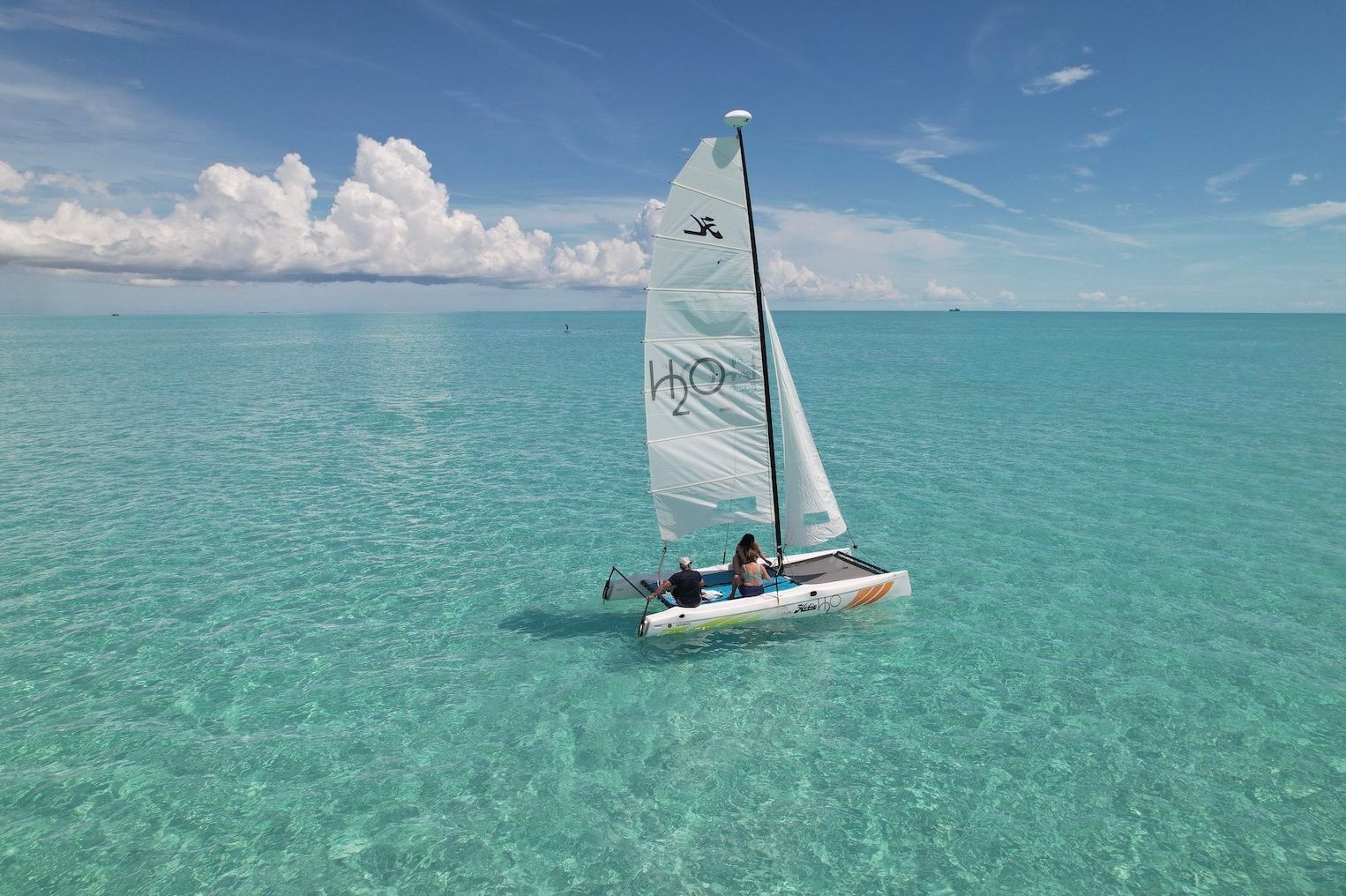 Couple sailing an H2O branded catamaran on calm turquoise water
