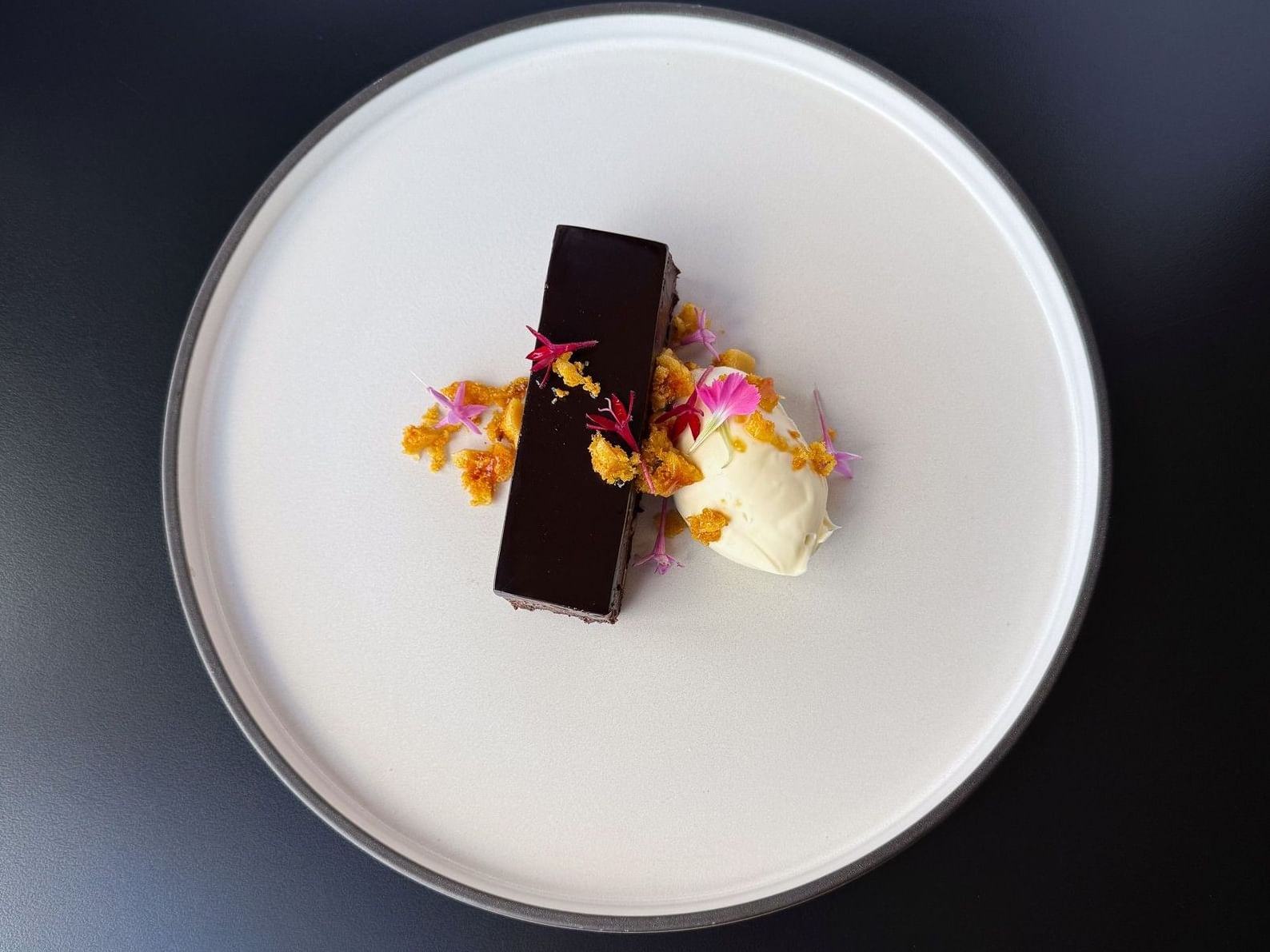 Artfully plated chocolate dessert with gold honeycomb and pink floral garnish, highlighting the fine dining experience at Frescos Restaurant