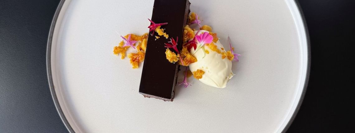Elegant plated chocolate dessert with cream, edible flowers, and crumble garnish served at a corporate dining event at Hotel Grand Chancellor Brisbane.