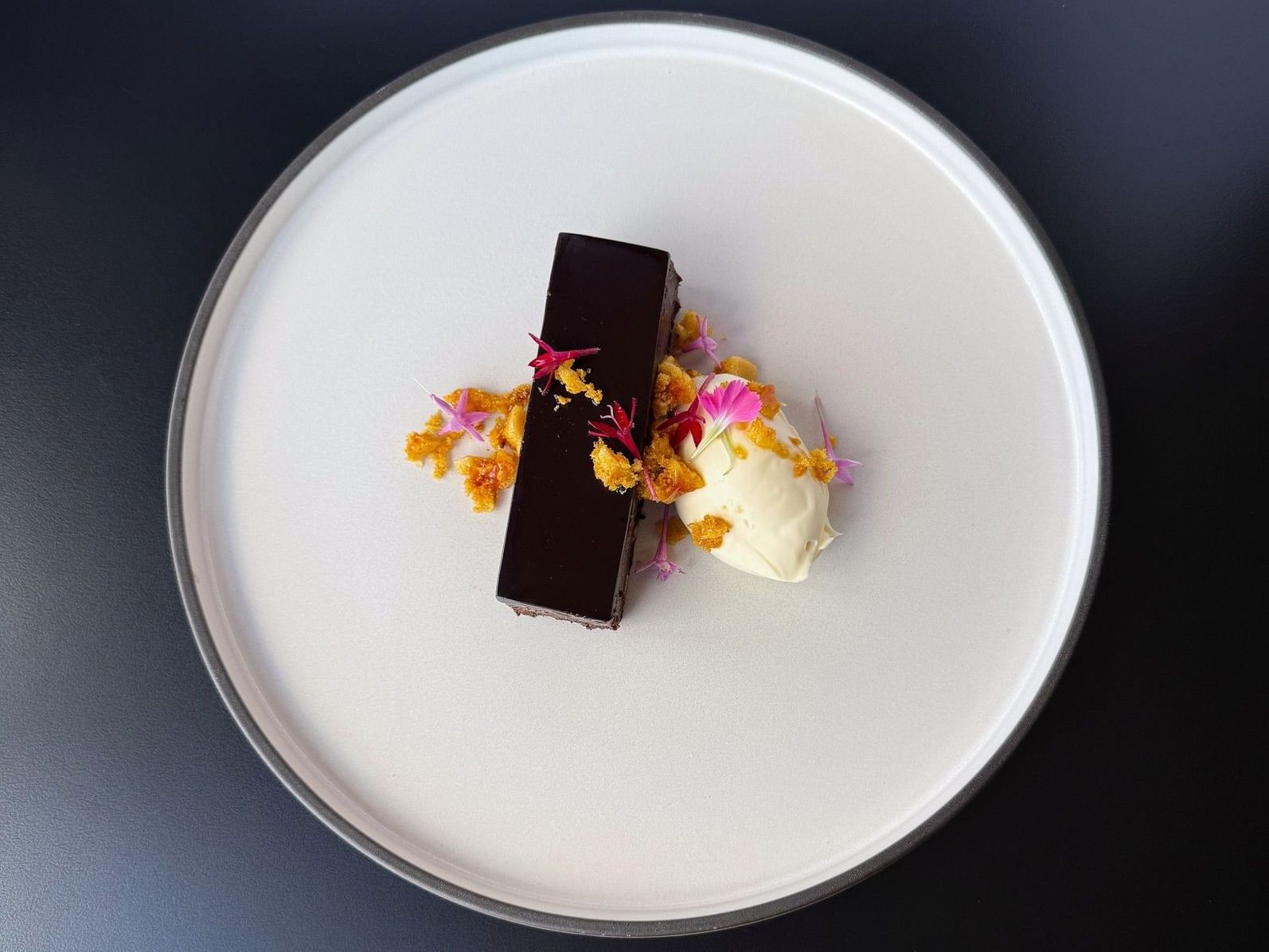 Elegant plated chocolate dessert with cream, edible flowers, and crumble garnish served at a corporate dining event at Hotel Grand Chancellor Brisbane.