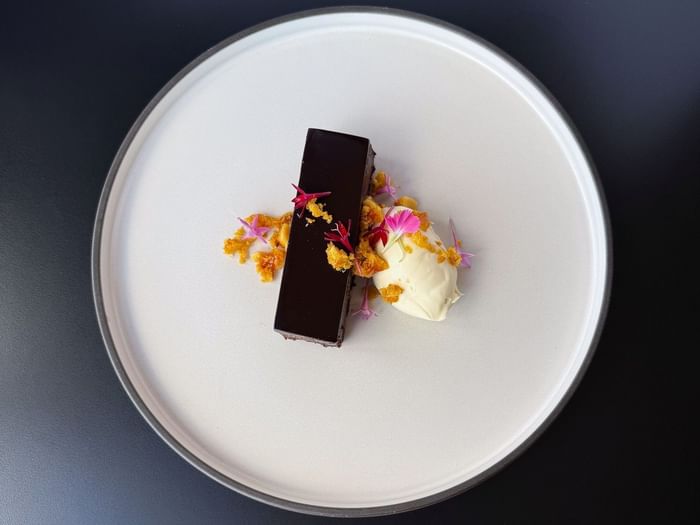 Elegant plated chocolate dessert with cream, edible flowers, and crumble garnish served at a corporate dining event at Hotel Grand Chancellor Brisbane.