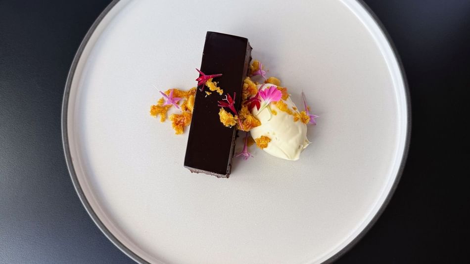Elegant plated chocolate dessert with cream, edible flowers, and crumble garnish served at a corporate dining event at Hotel Grand Chancellor Brisbane.