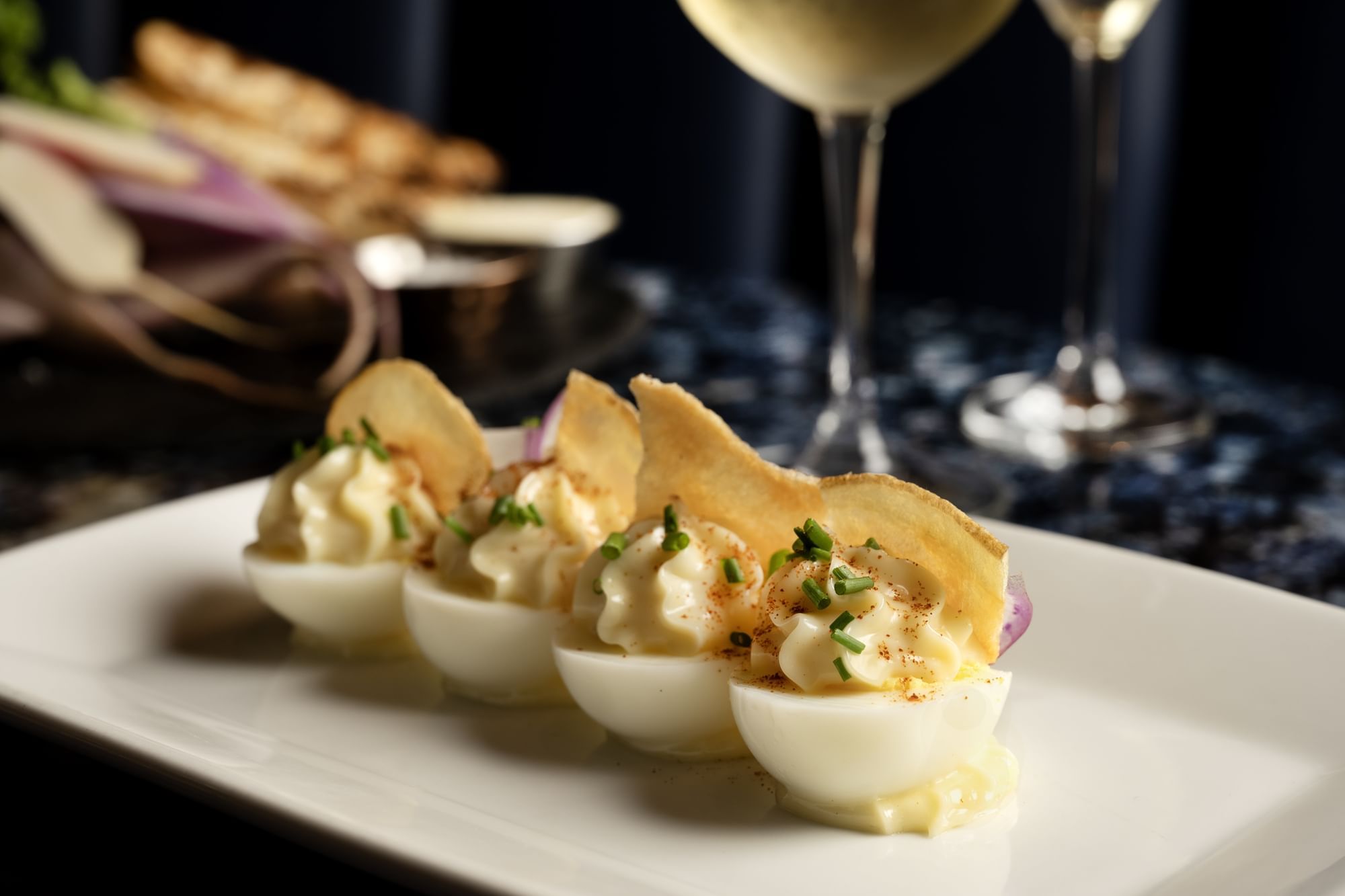 A plate of 4 Deviled Eggs with free-range egg, mustard, mayonnaise, radish, espelette pepper, chive