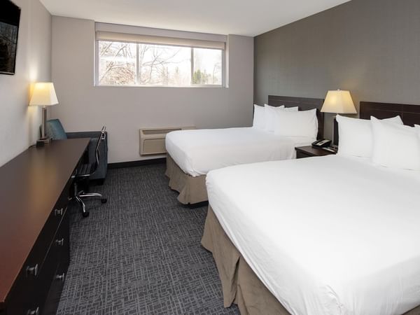 Two queen beds in a room with a desk and TV.