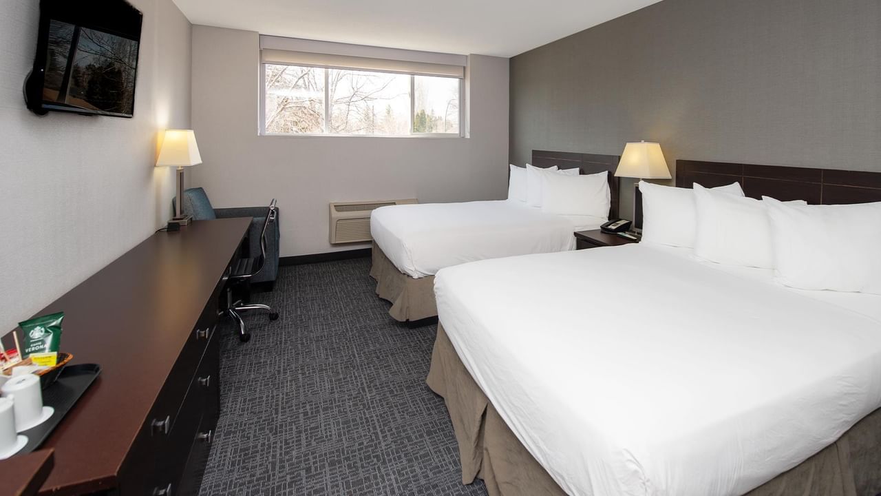 Two queen beds in a room with a desk and TV.