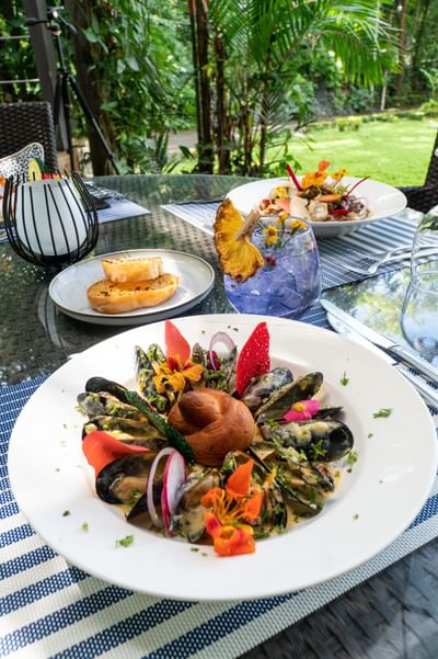Platos de ostras servidos con tostadas y una bebida de cóctel en una mesa en Karolas Restaurant & Bar en Los Altos Resort