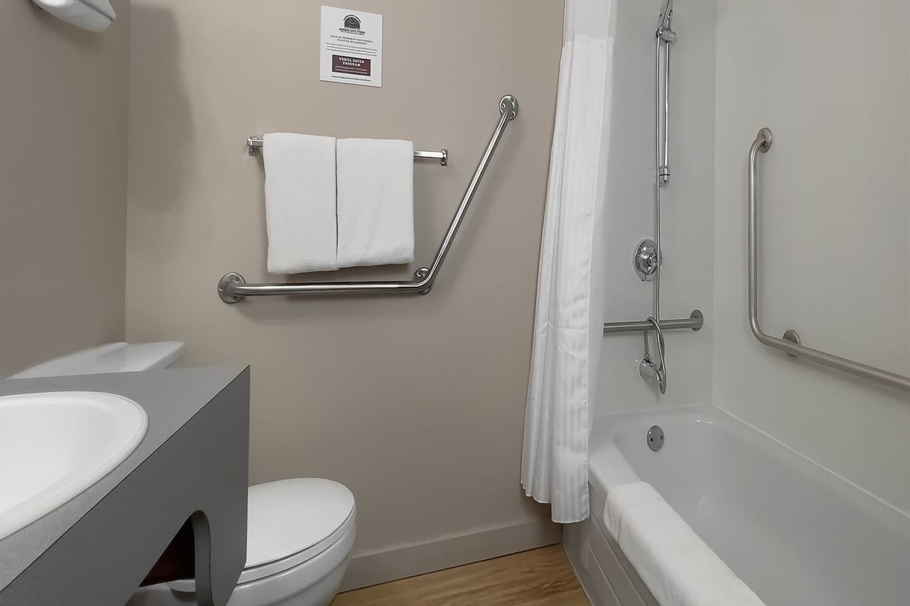 Bathroom with towels, toilet, mirror, bath and sink