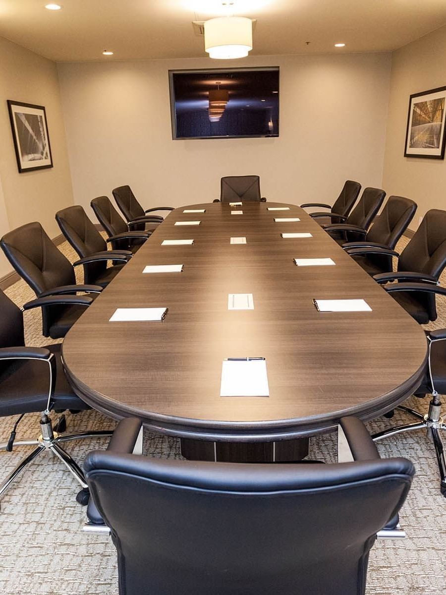 Black chairs by a long oval table under a flat-screen TV in Encore Room at Warwick San Francisco