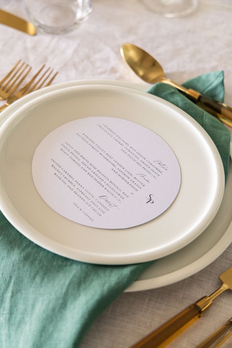 Elysium Manly event table setting featuring a circular menu card resting on a plate next to elegant dining utensils