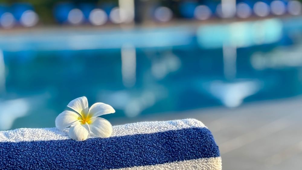 White flower on blue and white towel by pool at The Naviti Resort Korolevu Fiji.