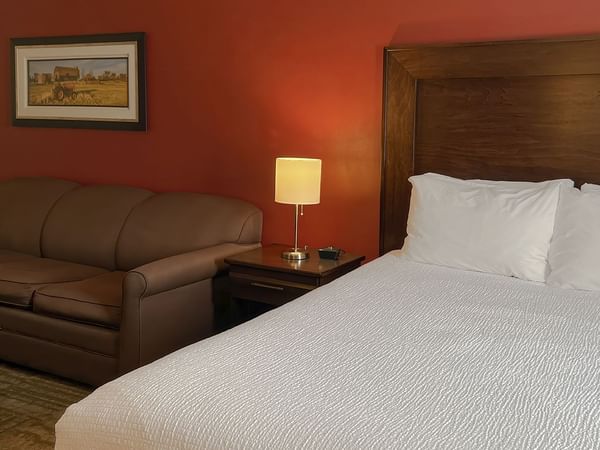 Hotel bedroom with bed, couch, lamp, and table