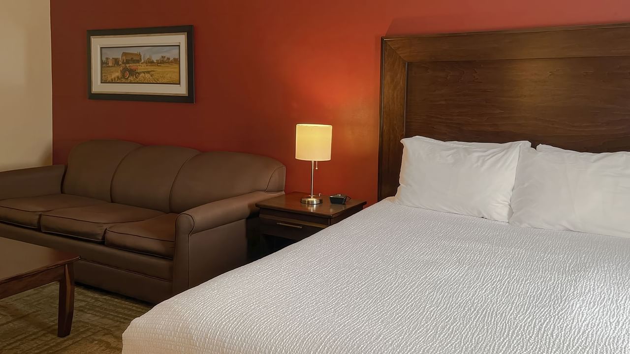 Hotel bedroom with bed, couch, lamp, and table
