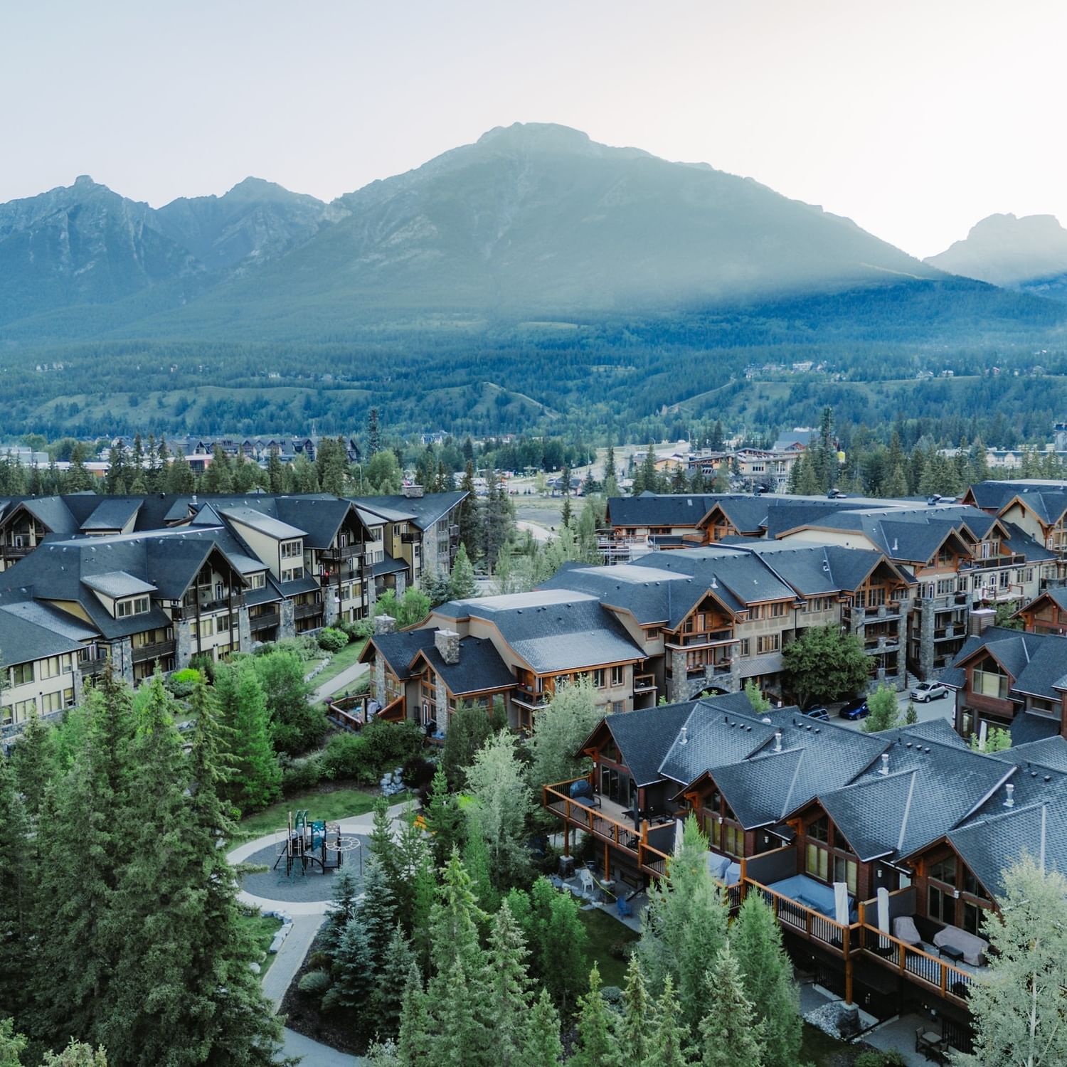 Aerial view of Spring Creek Resorts nestled among evergreen trees with dramatic Rocky Mountain peaks in the background