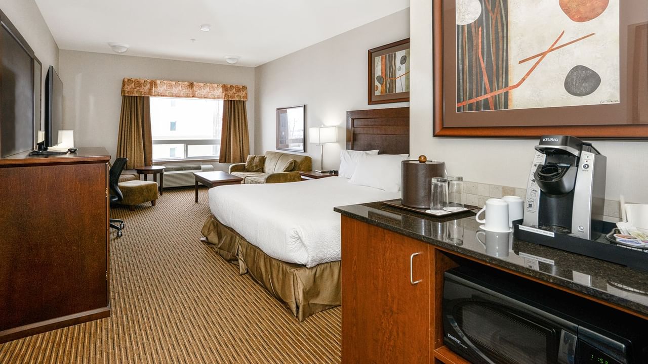 Hotel room with a king bed and a sofa bed, TV, work desk, chair, coffee machine and microwave