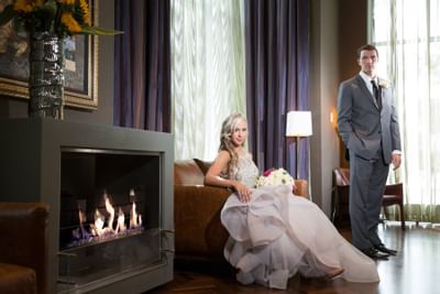 A bride and groom lounging by a fireplace