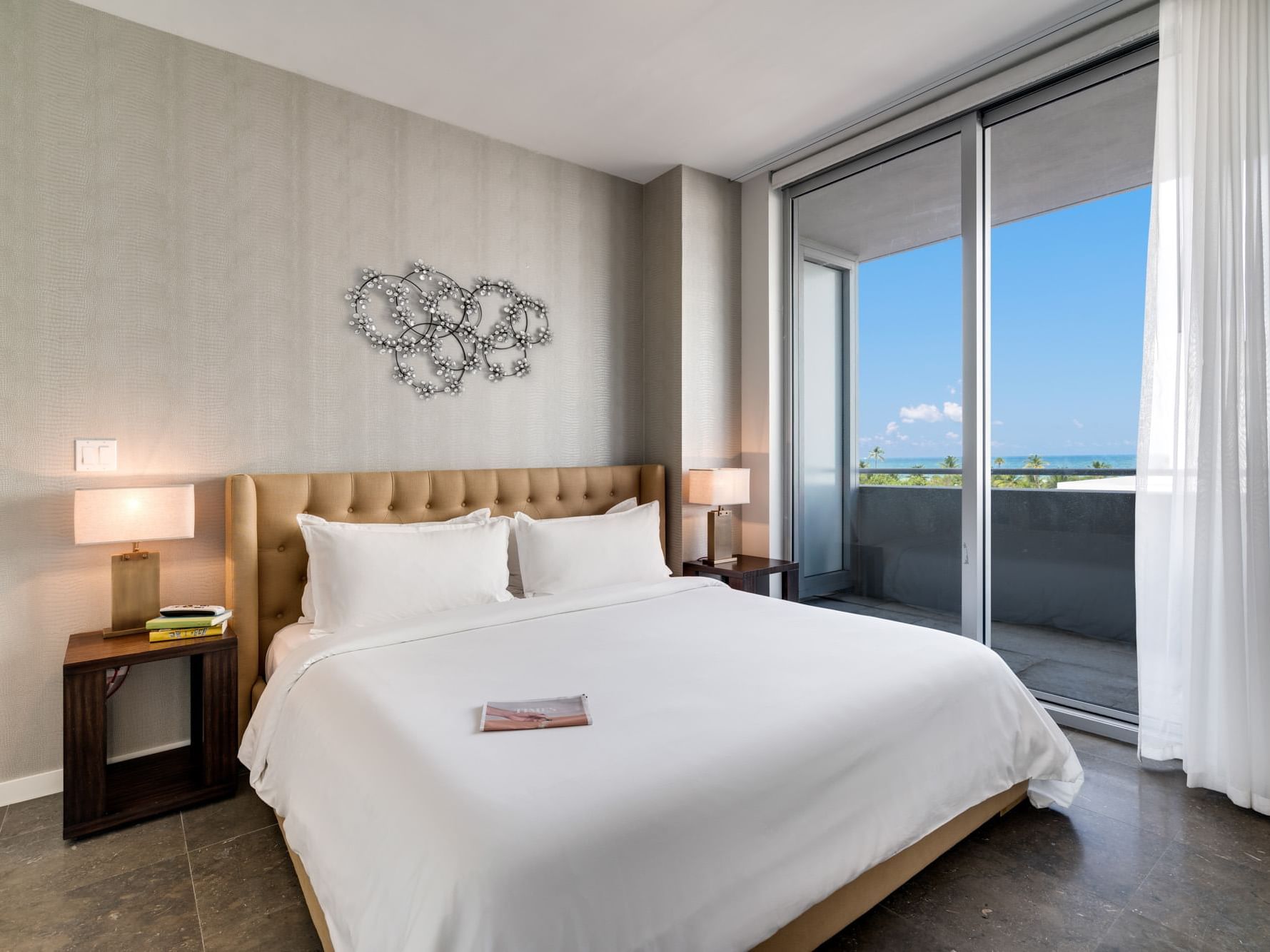room with beige bed, white bedding and balcony