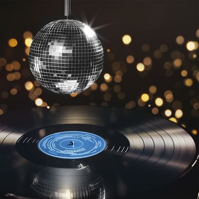 Disco ball hanging above a spinning vinyl record with a dark background and bokeh lights.