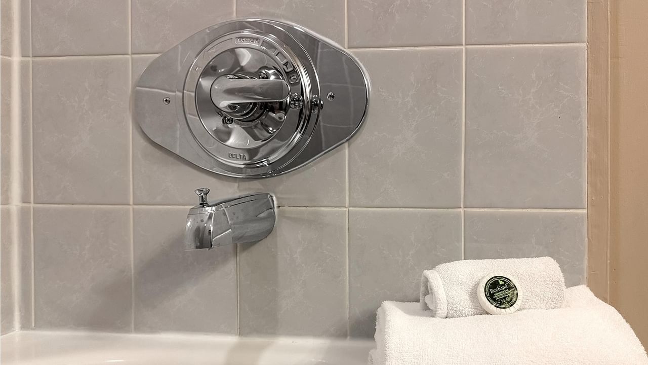 Bathtub with modern faucet and white towels.