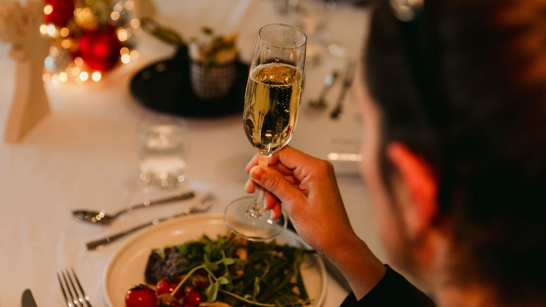 Person at a table with a champagne glass and plate of food.
