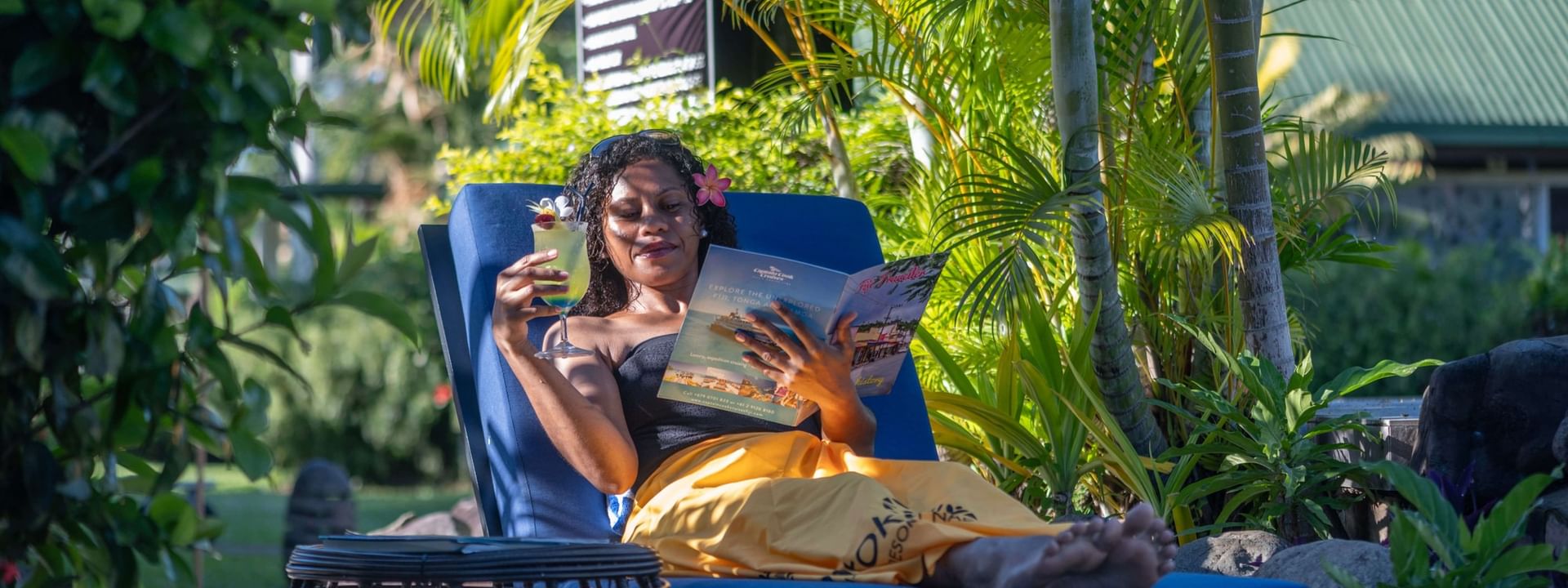 Guest reading a brochure on a blue lounger surrounding tropical palms at TokaToka Resort Nadi Fiji