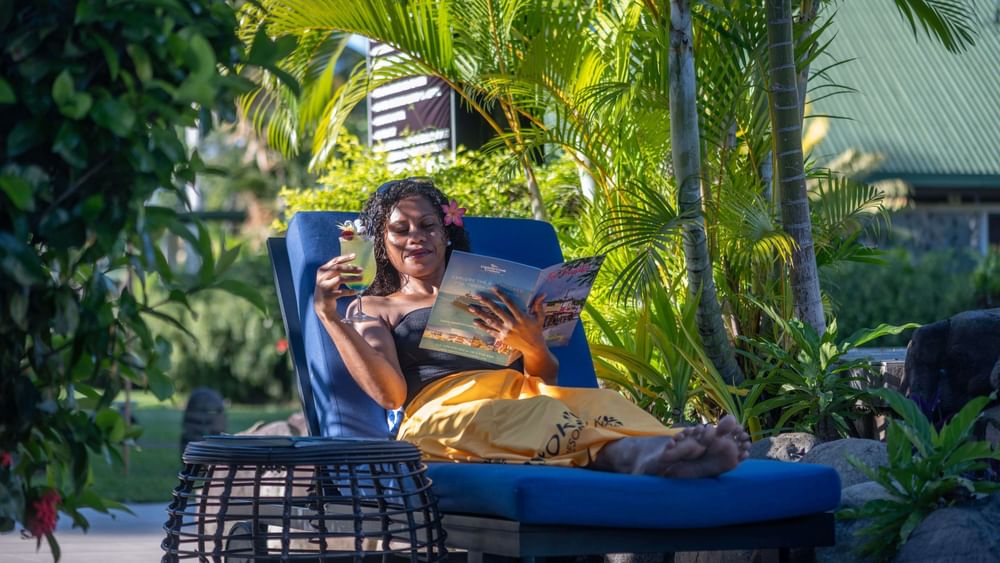 Guest reading a brochure on a blue lounger surrounding tropical palms at TokaToka Resort Nadi Fiji