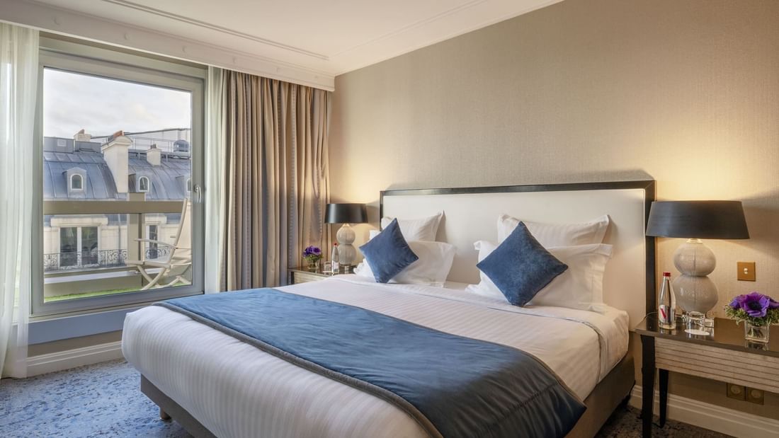 Neat bed with blue pillows by silver ball lamps in The Champs-Élysées Suite at Warwick Paris Champs Elysées