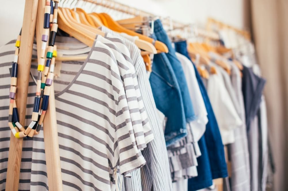 A straight-on shot of a rack with white, blue, and gray clothing items.