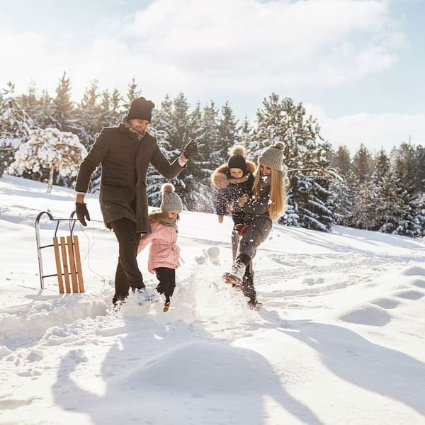 Family enjoying ice skating together on a snowy day near Falkensteiner Schlosshotel Velden