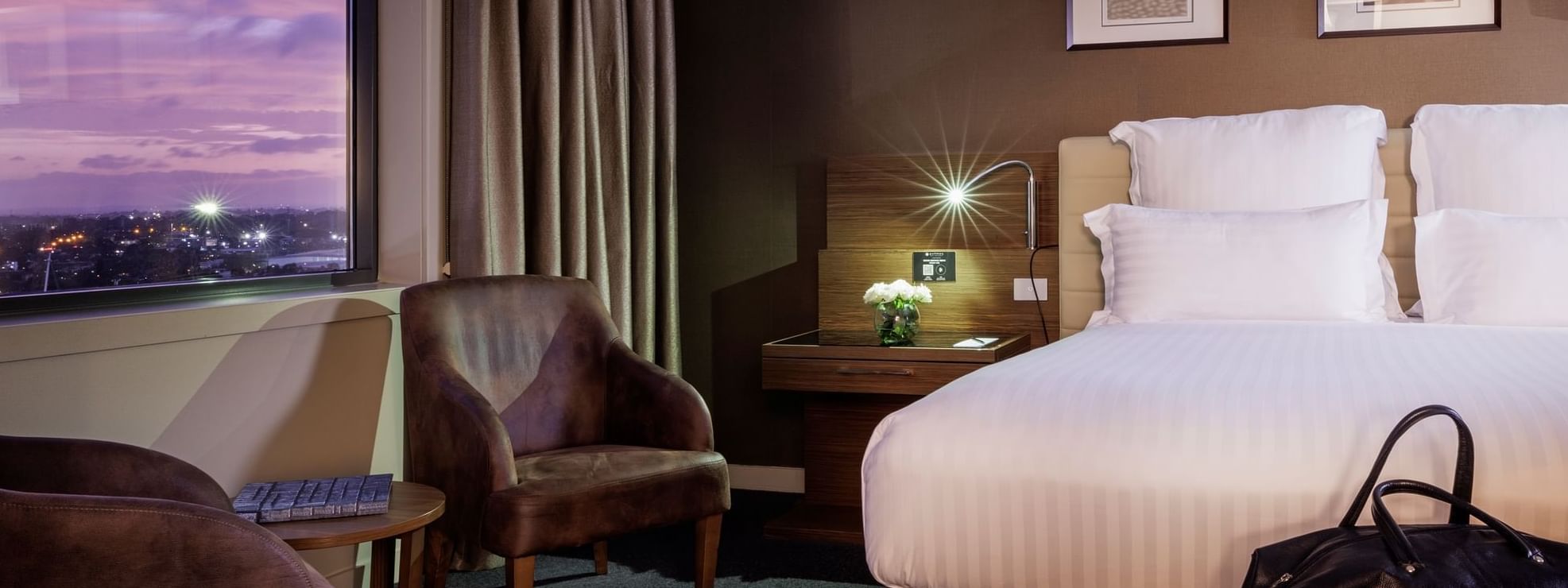 Bed with a couch by the windows and carpet floors in the Pullman Suite Bedroom at Pullman Sydney Olympic Park