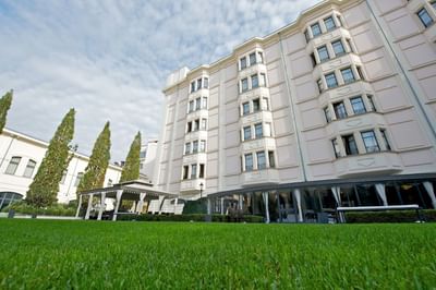 Low-angle view of the hotel exterior & green lawn in the garden at Grand Visconti Palace