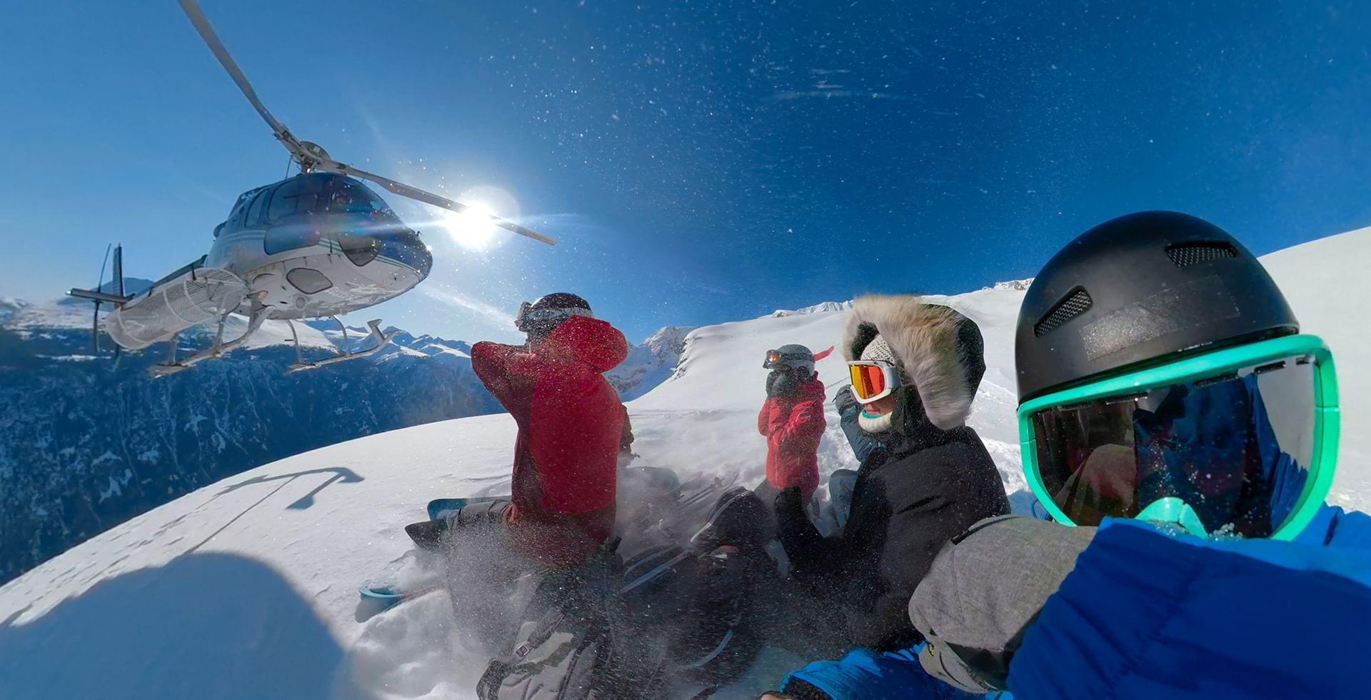 Helicopter and skiers on top of a mountian