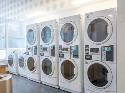 Row of high-efficiency stacked washers and dryers in a clean, well-lit on-site laundry room.