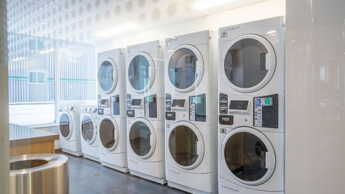 A bright laundry facility with washing machines, driers, plenty of counter space and large windows that let in a lot of light.