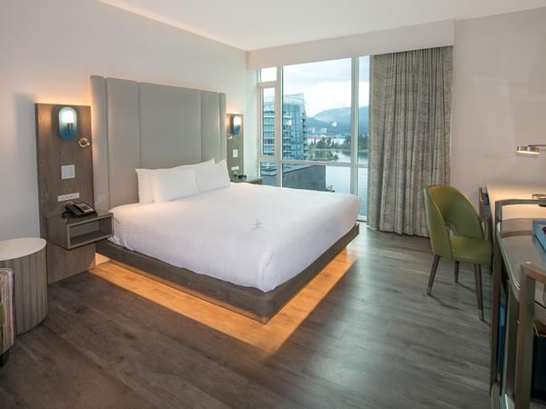 A hotel room with a king bed, desk, and view.