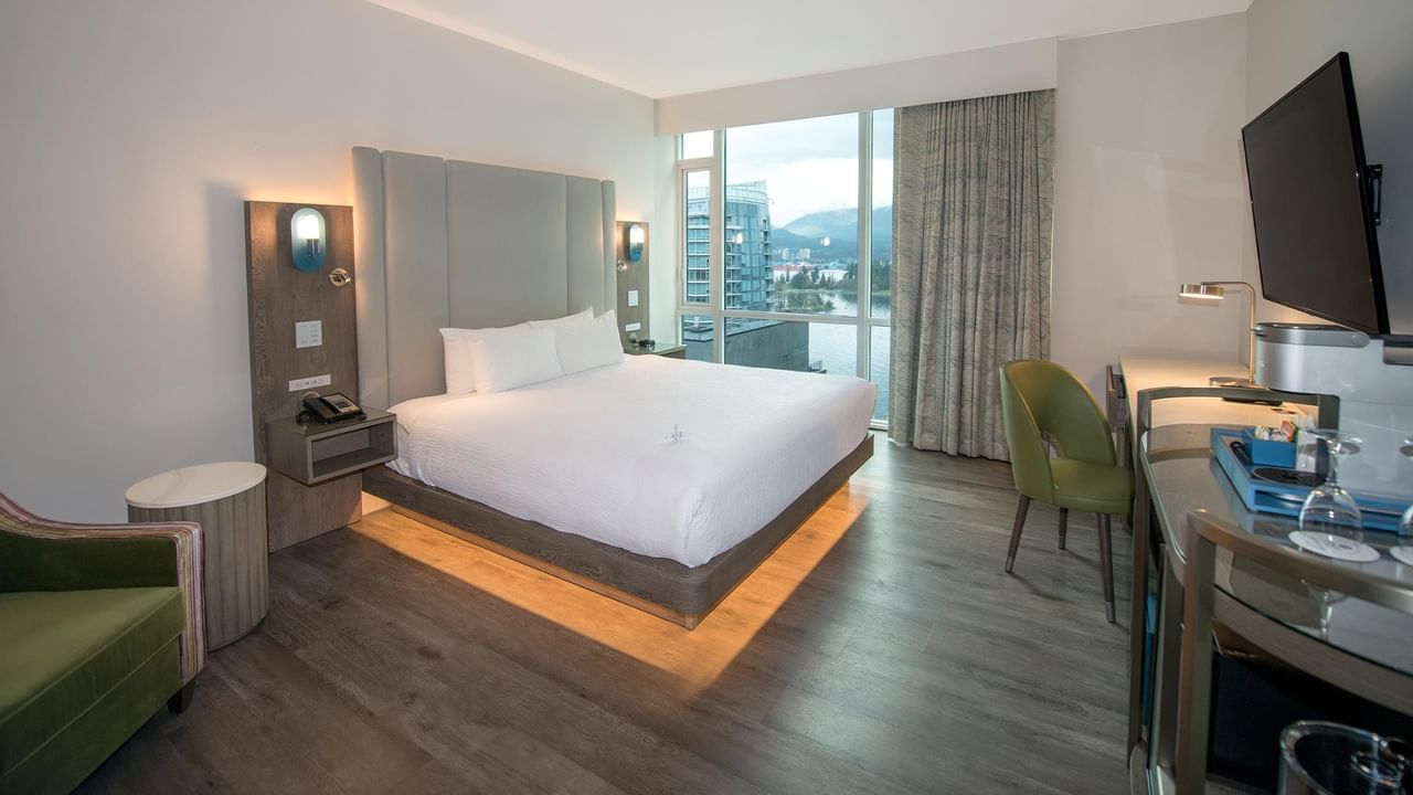 A hotel room with a king bed, desk, and view.