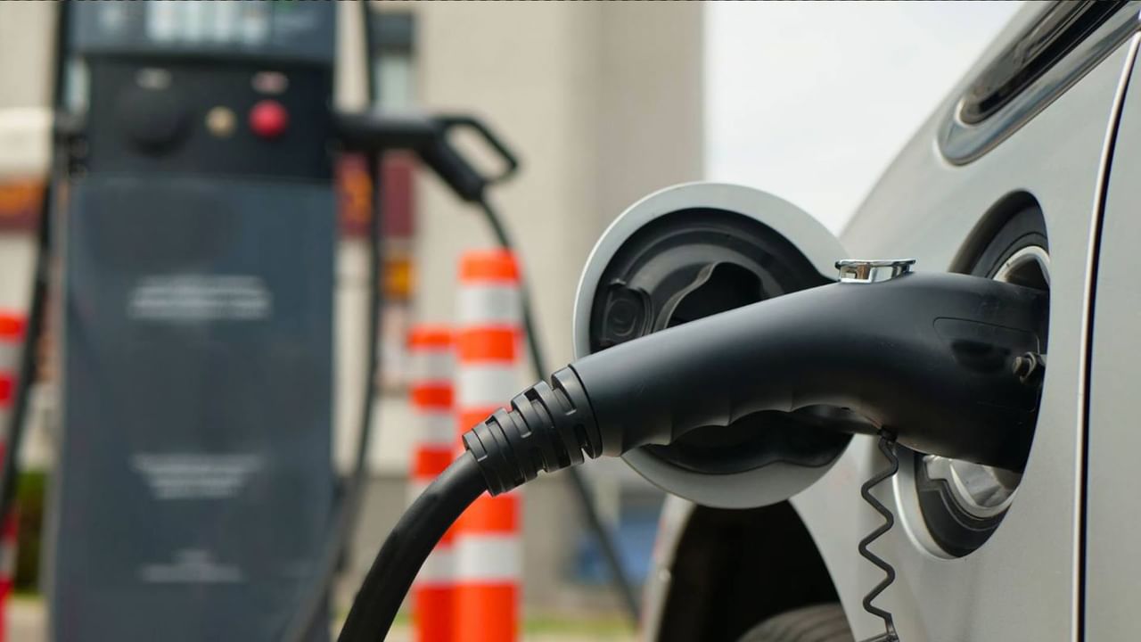 Electric car charging at a station with a black cable connected to the charging port.