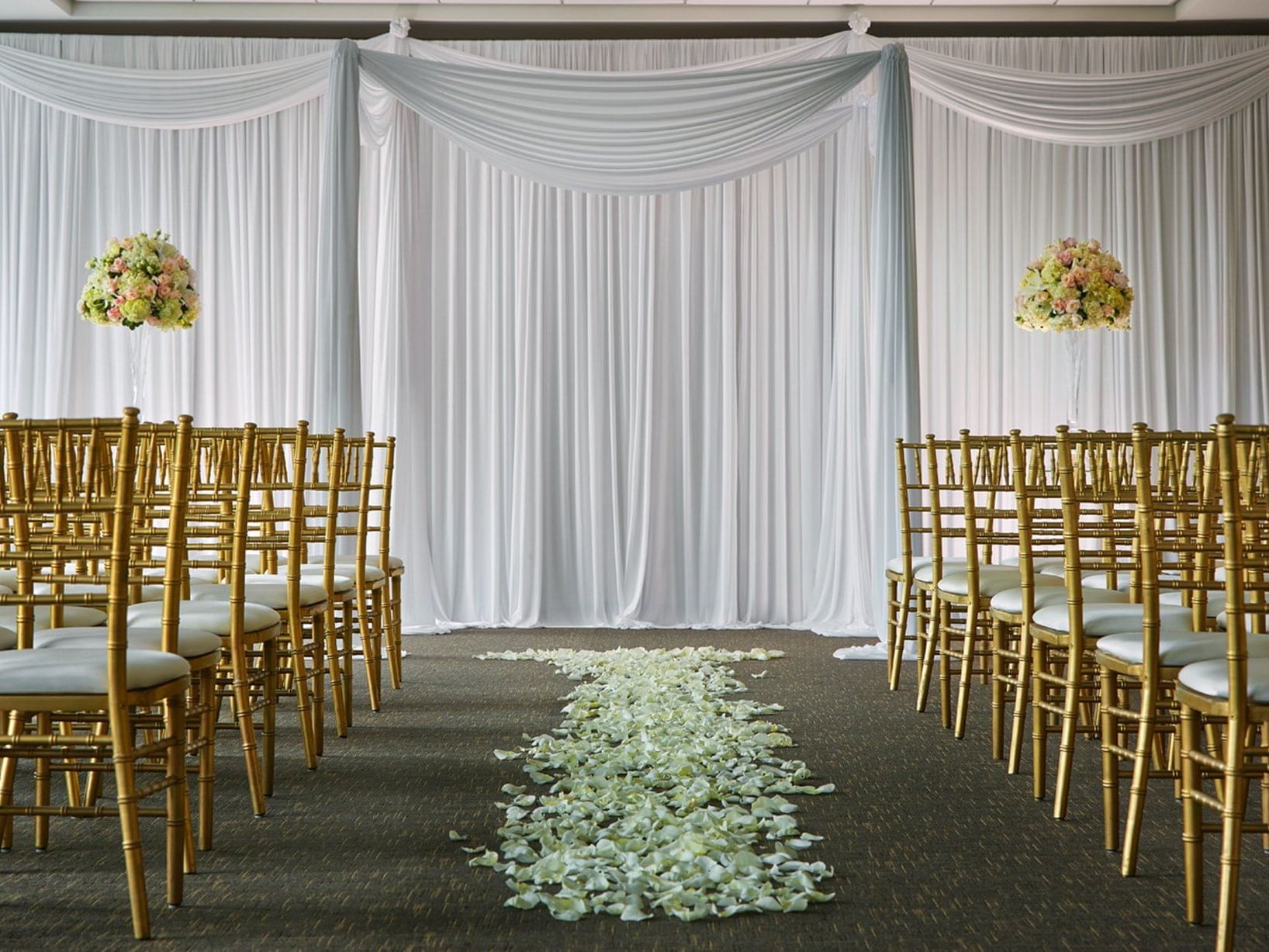 Elegantly decorated event space with gold chairs and white petals at Hotel Arista in Naperville.