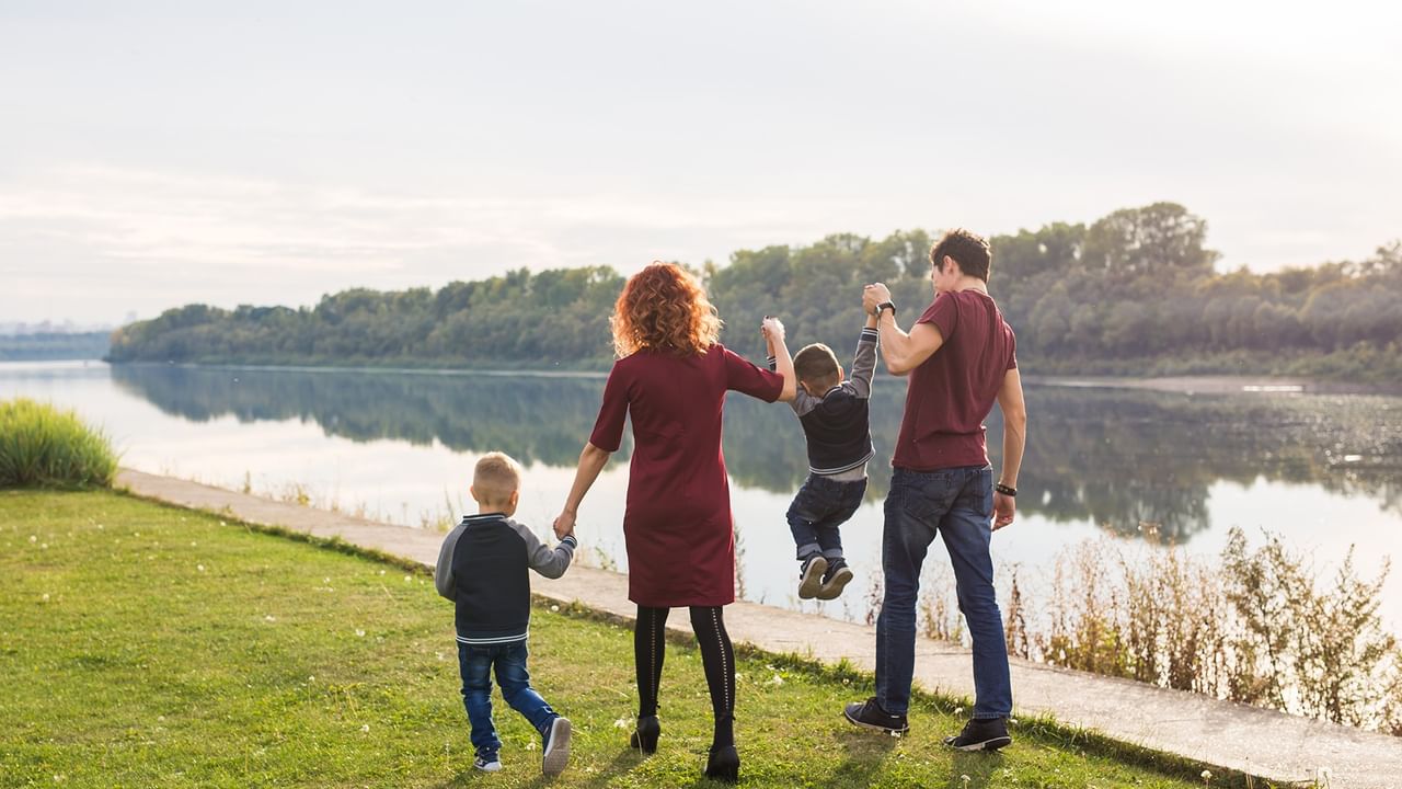 Family of four walking hand in hand along a river path with trees in the background for Members: Midweek Savings
