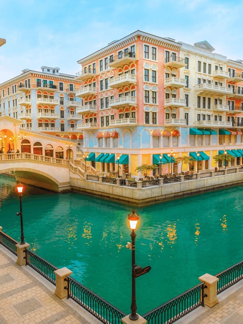The Pearl by colorful buildings surrounding a turquoise canal under a soft sky near Warwick Doha Hotel