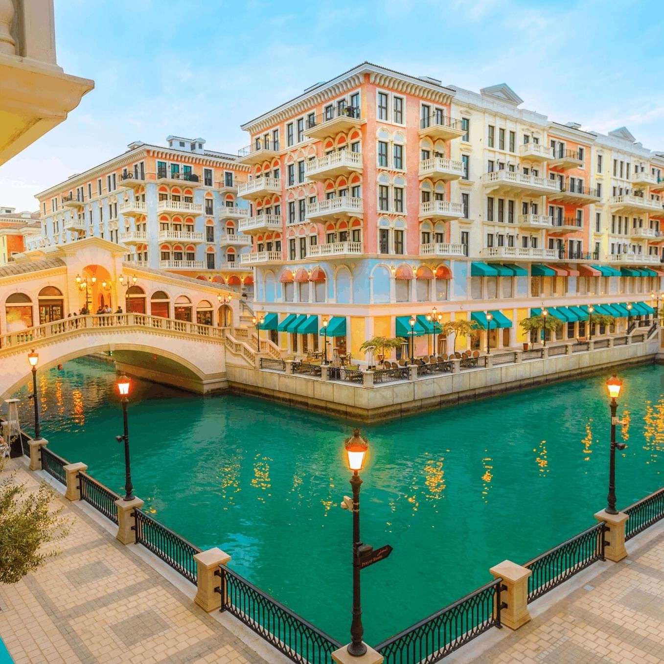 The Pearl by colorful buildings surrounding a turquoise canal under a soft sky near Warwick Doha Hotel