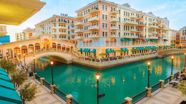 The Pearl by colorful buildings surrounding a turquoise canal under a soft sky near Warwick Doha Hotel