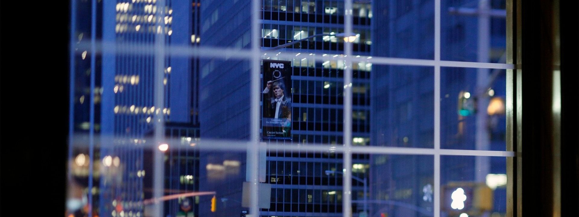 Nighttime view through window of glowing city skyscrapers and street traffic in Randolph's Bar & Lounge at Warwick New York
